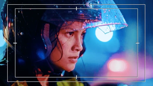 Graded frame in the Premiere program monitor: Lia in her helmet in the rain with cyan highlights and pink bokeh